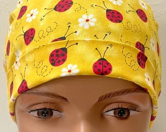 May include: A yellow scrub hat with a pattern of red ladybugs and white flowers.