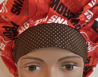 May include: A red and brown scrub hat with a polka dot pattern. The hat has the words "Browns" and "Cleveland Browns" printed on it.