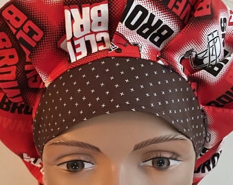 May include: Red and brown surgical scrub hat with a repeating pattern of the words "Cleveland Browns" and "CLE BRO".