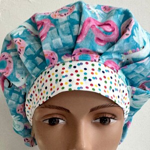May include: A blue and white scrub hat with a donut and sprinkles pattern. The hat has a white band with colorful polka dots.