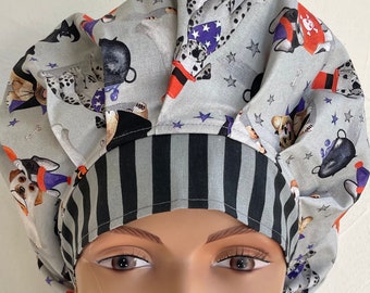 May include: A gray and black striped scrub hat with a gray fabric top featuring a pattern of dogs dressed in Halloween costumes. The dogs are wearing hats, costumes, and holding props.