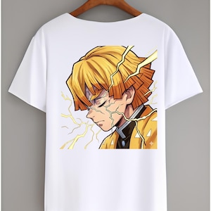 May include: A white short-sleeved t-shirt featuring a graphic print of an anime character with short yellow hair and orange tips. The character has closed eyes and is surrounded by yellow lightning bolt illustrations on a white background.