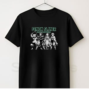 May include: A black short-sleeved t-shirt featuring a graphic print of four anime characters from Demon Slayer Kimetsu no Yaiba. The text DEMON SLAYER KIMETSU NO YAIB A is printed in a light green font above the characters, who are depicted in black and white.