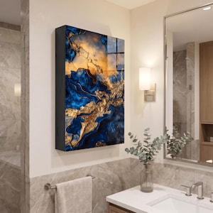May include: A rectangular wall-mounted cabinet featuring a glossy front panel with an abstract design of swirling deep blue and metallic gold veins. The cabinet has a solid black frame and is mounted on a light-colored wall in a bathroom setting.