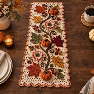 Pode incluir: Um caminho de mesa retangular de crochê na cor creme com um padrão intrincado de videira, abóboras laranja tridimensionais, folhas de outono multicoloridas em tons de vermelho, amarelo e verde, pequenas bagas e uma borda laranja festonada.