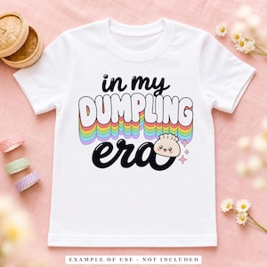 A white t-shirt with the text "in my DUMPLING era" in colorful, arched letters, featuring a small smiling dumpling graphic.