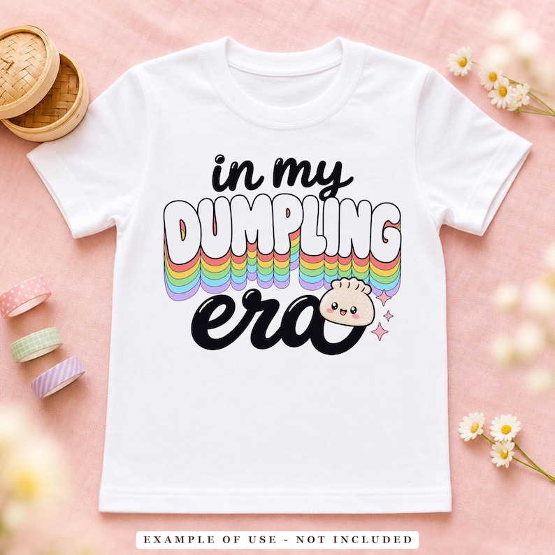 A white t-shirt with the text "in my DUMPLING era" in colorful, arched letters, featuring a small smiling dumpling graphic.