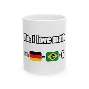 Może przedstawiać: Biały ceramiczny kubek z napisem "Me: I love math" i "Math:" oraz flagami Niemiec i Brazylii oraz cyfrą 6. Kubek jest cylindryczny i ma prosty design.