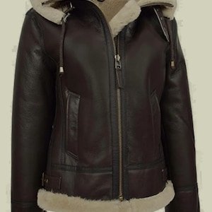 May include: A dark brown leather jacket with a cream-coloured shearling lining and hood. The jacket features a front zip closure, two side pockets, and adjustable straps at the waist. The brand name BLACKFORGE is printed in the top right corner.