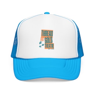 May include: A blue and white trucker hat with a curved brim. The hat features a white front panel with the text "THREAD and GOLD THEATRE" in orange and teal. The hat has a blue mesh back and a blue brim.