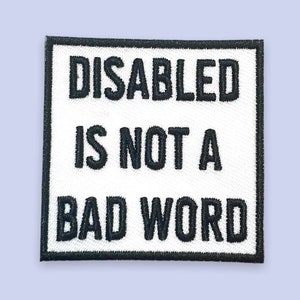 May include: Square patch with the embroidered text "DISABLED IS NOT A BAD WORD" in black on a white background. The patch has a black border and is set against a light purple background.