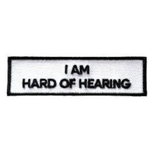 Peut inclure: Écusson rectangulaire blanc avec une bordure noire et le texte "I AM HARD OF HEARING".