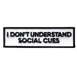 May include: White rectangular patch with black border and text that reads "I don't understand social cues".