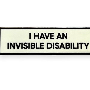 May include: A rectangular pin with a black border and a cream-colored background. The pin features the text "I HAVE AN INVISIBLE DISABILITY" in bold, black capital letters. This pin is designed to raise awareness.
