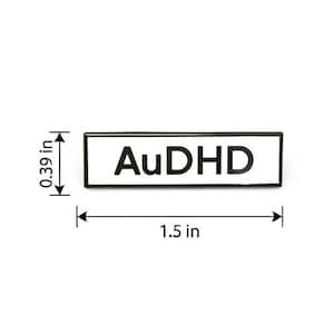 May include: A rectangular enamel pin with a white background and a black border featuring the black text AuDHD. The pin measures 1.5 inches in width and 0.39 inches in height as indicated by the black dimension lines and arrows shown in the image.