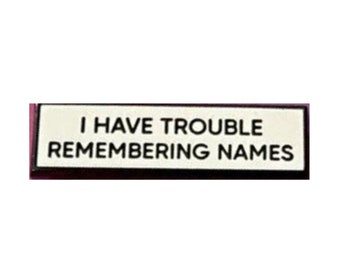 May include: A white rectangular sign with black text that reads "I have trouble remembering names".