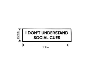 May include: A rectangular black and white pin featuring the text I DON'T UNDERSTAND SOCIAL CUES. The pin is measured with arrows indicating a height of 0.39 inches and a width of 1.5 inches, providing clear visual dimensions for this accessory.