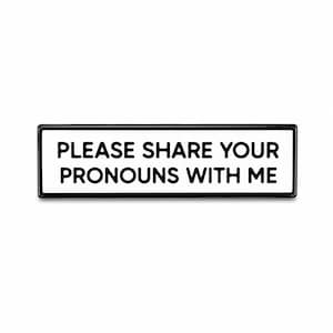 May include: A rectangular enamel pin with a white background and a thick black border. The text PLEASE SHARE YOUR PRONOUNS WITH ME is printed in bold black sans-serif capital letters across the center of the pin, creating a clear message.