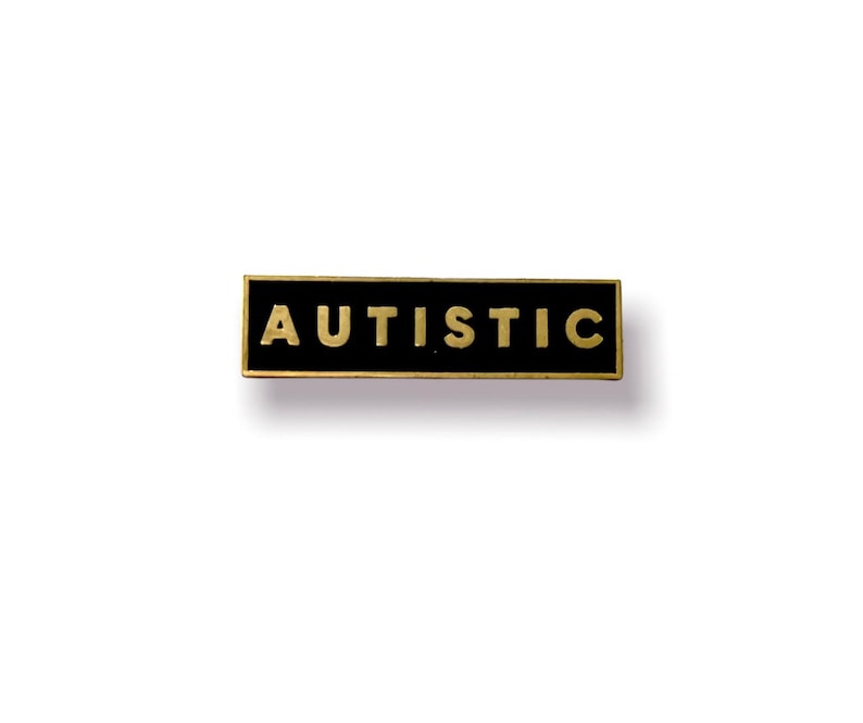 May include: Black rectangular pin with gold lettering that reads "AUTISTIC".