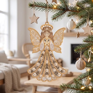 Puede incluir: Un adorno colgante de ángel hecho de madera clara con detalles intrincados cortados con láser. El ángel presenta un halo, cabello trenzado y manos juntas en oración. El vestido está decorado con patrones florales y bordes festoneados.