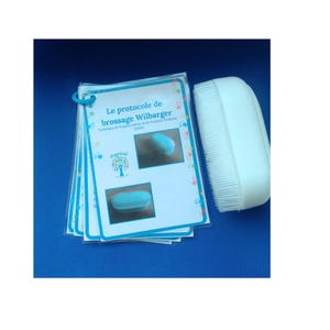 Peut inclure: Un ensemble de cartes avec le texte "Le protocole de brossage Wilbarger" et une brosse blanche à poils. Les cartes présentent des images d'un objet bleu. Le fond est bleu uni.