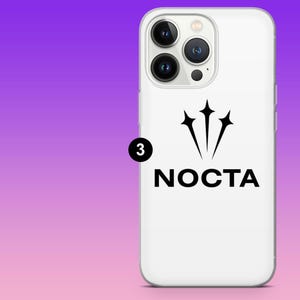 K&ouml;nnte beinhalten: Wei&szlig;es Handycase mit schwarzem Logo. Das Logo zeigt drei sternf&ouml;rmige Formen &uuml;ber dem Wort "NOCTA". Das Case hat eine gl&auml;nzende Oberfl&auml;che und einen Kameraausschnitt. Der Hintergrund ist ein Farbverlauf aus Lila und Rosa.