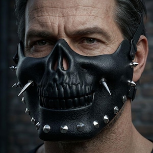 Könnte beinhalten: Schwarze Leder-Totenkopfmaske mit silbernen Stacheln und Nieten. Die Maske hat ein detailliertes Totenkopfdesign mit Nase und Zähnen. Sie hat einen Riemen zum Befestigen am Kopf. Ein gotisches Accessoire.
