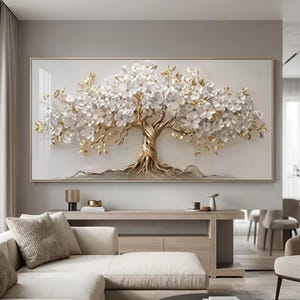 Puede incluir: Una pieza de arte mural rectangular que presenta un árbol tridimensional con un tronco y ramas de color oro metálico. El árbol está adornado con numerosas flores blancas en capas y pequeñas hojas doradas sobre un fondo de color claro.