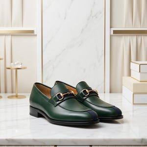 May include: A pair of dark green leather loafers featuring a gold-toned metal horsebit detail across the vamp and a navy blue vertical stripe accent on the toe. The shoes have a low black heel and a smooth, polished finish on the exterior leather.