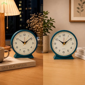 May include: A round analog table clock with a teal frame and a cream-colored face. The clock features black Arabic numerals, black hour and minute hands, a thin red second hand, and the word QUARTZ printed in black below the center hands.