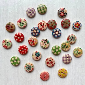 Può includere: Una collezione di venticinque bottoni rotondi in legno con vari motivi colorati, tra cui pois, disegni floreali, quadretti vichy e motivi geometrici. Ogni bottone presenta due fori al centro per il fissaggio su tessuti o indumenti.
