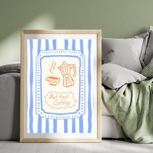 May include: A framed wall art print featuring a light blue vertical striped background. The center displays a cream-colored rectangular border containing an orange line drawing of a moka pot and a coffee cup, with the text But first Coffee.
