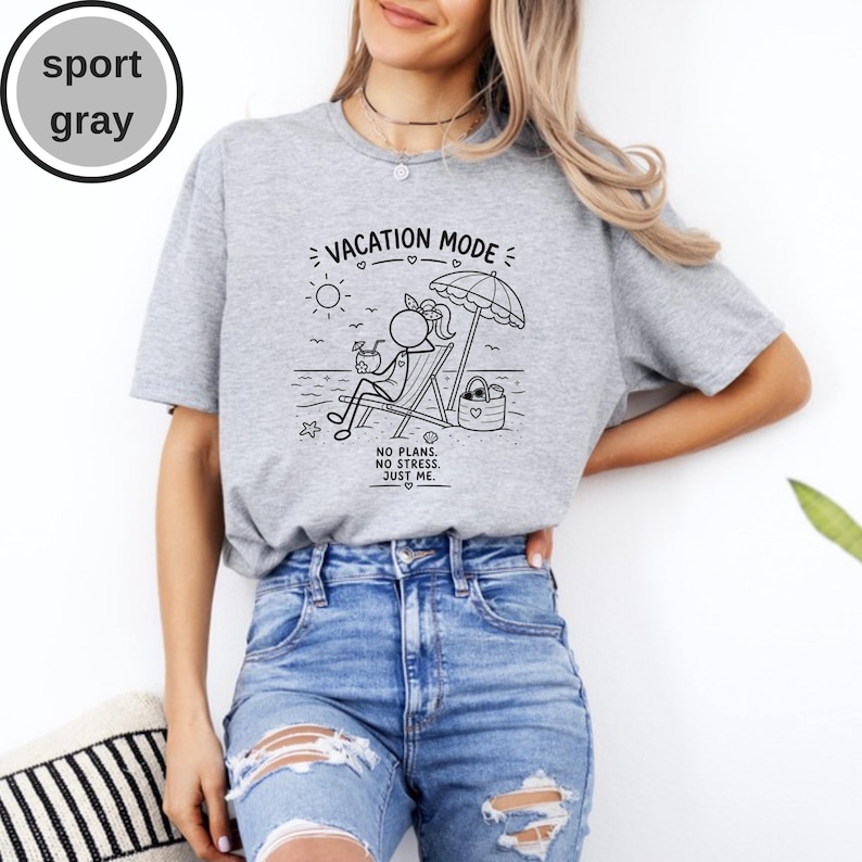 May include: Sport gray t-shirt with a black graphic of a person relaxing on a beach chair under an umbrella, with the text "VACATION MODE" and "NO PLANS. NO STRESS. JUST ME." printed on the front. The shirt is paired with blue jeans.