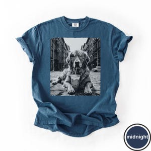 Peut inclure: Un t-shirt bleu fonc&eacute; &agrave; manches courtes avec une impression graphique en noir et blanc repr&eacute;sentant un chien portant des lunettes de soleil et buvant dans un gobelet en plastique avec une paille, au milieu d'une rue bord&eacute;e d'immeubles.