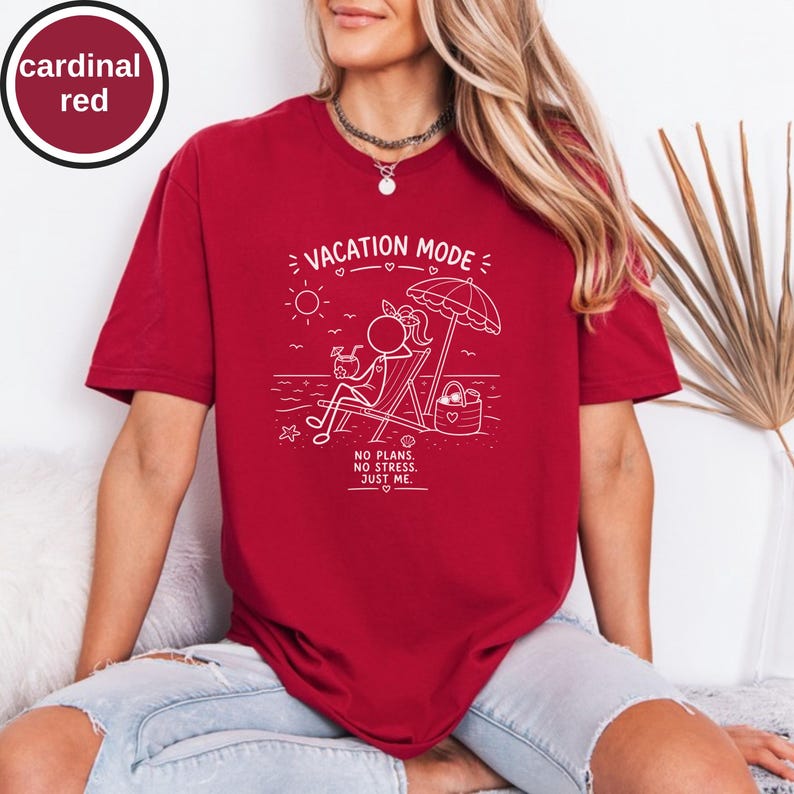 May include: Cardinal red t-shirt with a white graphic that reads "VACATION MODE" above a stick figure relaxing on a beach. The text "NO PLANS. NO STRESS. JUST ME." is below the graphic. The shirt has short sleeves.