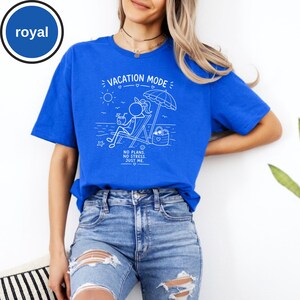 May include: Royal blue t-shirt with a white graphic that reads "VACATION MODE" and features a stick figure relaxing on a beach chair under an umbrella. The text "NO PLANS. NO STRESS. JUST ME." is also included. The shirt is made of a soft material.