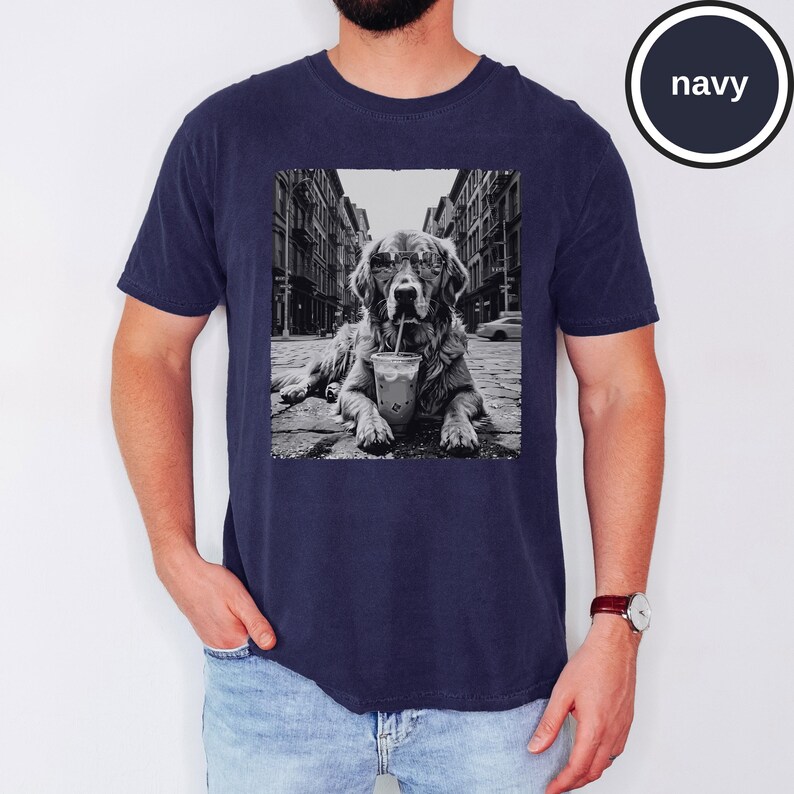 Peut inclure: Un t-shirt bleu marine avec une impression graphique en noir et blanc repr&eacute;sentant un chien portant des lunettes de soleil et buvant dans un gobelet en plastique avec une paille, sur fond de rue urbaine. Le mot navy est &eacute;crit dans un cercle.