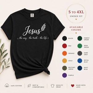 Può includere: Una t-shirt nera a maniche corte con testo bianco che recita Jesus the way - the truth - the life e una piccola grafica a foglia. La maglietta è mostrata accanto a una tabella colori con opzioni disponibili tra cui nero, rosso, arancione, oro, verde e blu.
