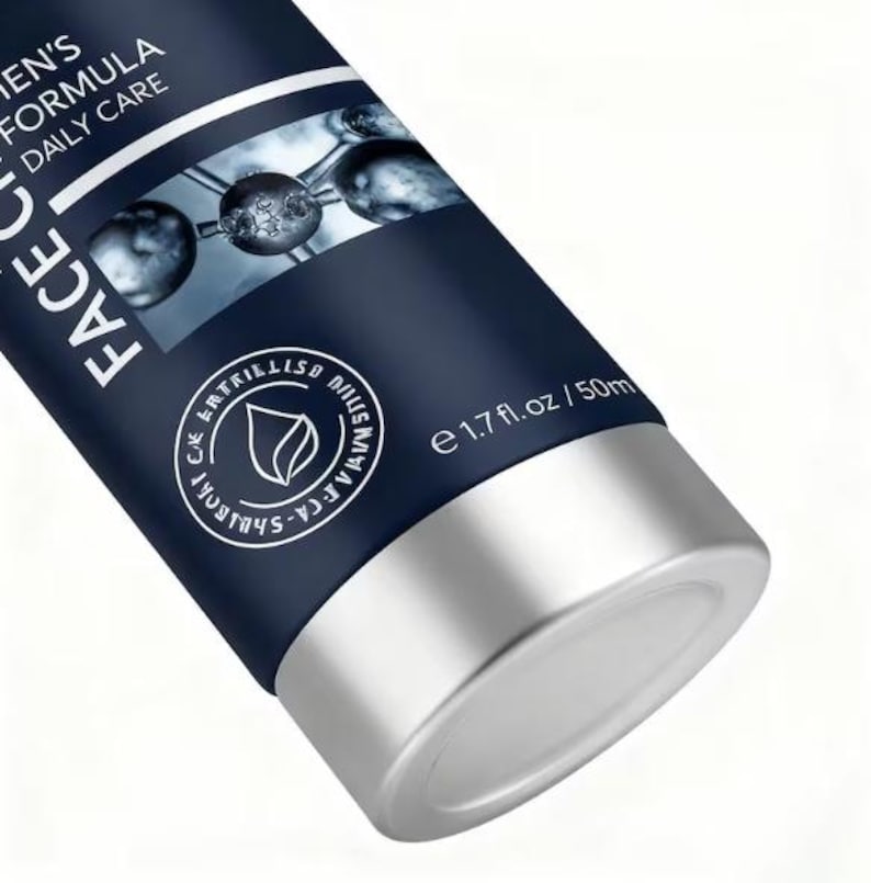Op de afbeelding: Een close-up van een donkerblauwe cosmeticale tube met zilveren accenten. De tube heeft witte tekst met de tekst "FACE" en "MEN'S FORMULA DAILY CARE". De tube heeft ook een cirkelvormig logo en de tekst "e 1.7 fl. oz / 50ml".