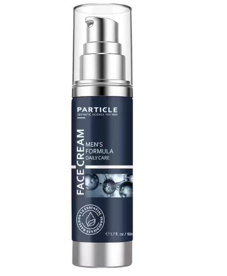 Op de afbeelding: Donkerblauwe gezichtscr&egrave;mefles met een zilveren pomp en voet. Het etiket leest "PARTICLE" en "MEN'S FORMULA DAILY CARE FACE CREAM". De fles bevat 50 ml product.