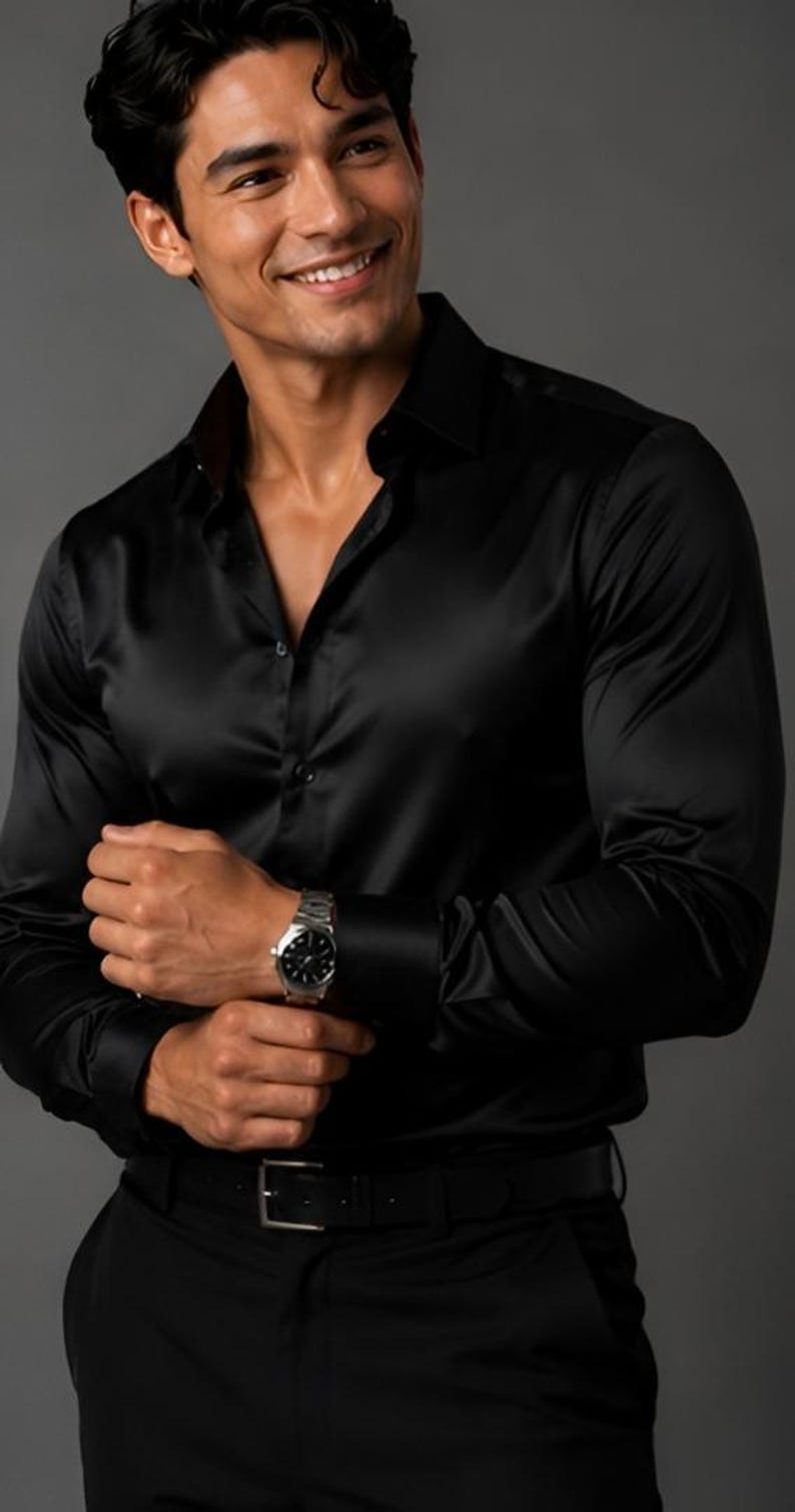 May include: A long-sleeved black button-down shirt with a smooth, satin-like finish, featuring a classic collar, buttoned cuffs, and a front button placket. The shirt is paired with a black belt and a silver-toned wristwatch with a black face.