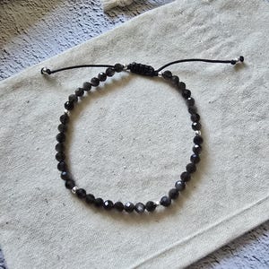 Bracciale artigianale in ossidiana nera sfaccettata, ossidiana con riflessi argentati, cristallo da 4 mm, argento sterling 925, cordino regolabile, cristallo protettivo.