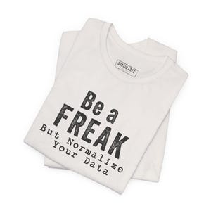 May include: A white short-sleeved t-shirt featuring the black text "Be a FREAK But Normalize Your Data" printed on the front. The shirt has a crew neckline and a small rectangular label inside the collar that reads "STATIC FREE".
