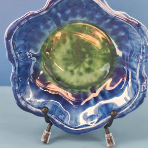 May include: A decorative ceramic bowl with a wavy, scalloped rim featuring a glossy finish. The centre of the bowl is a vibrant green, transitioning into deep blue and purple tones towards the edges, creating a swirling, marbled effect.