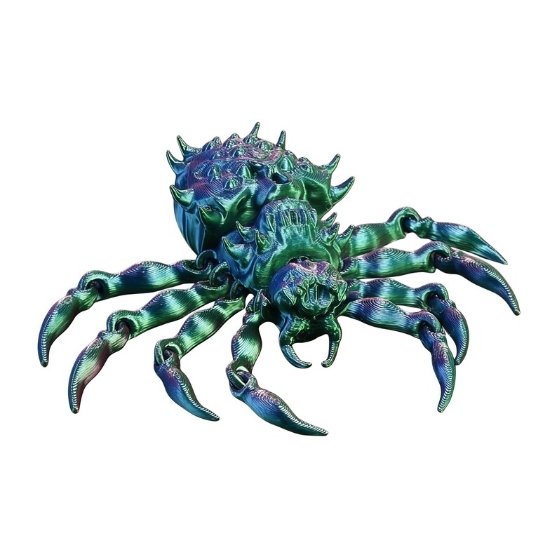 A teal blue‑and‑green holographic spider with iridescent highlights stands on a white background, its legs spread and body bristling with sculpted spikes.