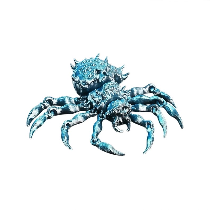 A bright chrome‑blue spider figurine with detailed textures, sharp claws and open mandibles is displayed on a clean white background.