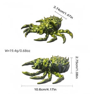 Two metallic yellow‑green spiders are shown on a white background with black measurements indicating a body width of 3.74 cm / 1.47 in, a height of 2.75 cm / 1.08 in, a length of 10.6 cm / 4.17 in and a weight of 19.4 g / 0.68 oz.