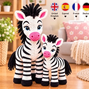 Puede incluir: Dos peluches de cebra hechos a mano con ganchillo, uno más grande y otro más pequeño, con cuerpos blancos de rayas negras, crines y colas negras, orejas y hocicos rosados, y grandes ojos azules con pestañas largas, de pie juntos.