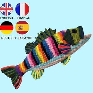 May include: A crocheted fish toy featuring a vibrant rainbow-striped body with horizontal bands of red, orange, yellow, green, blue, and purple. The fish has a dark green head, a black eye, and multi-colored fins and tail with a light blue belly.