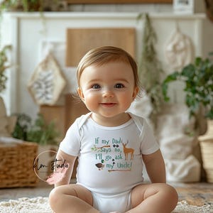 May include: A smiling baby wearing a white onesie with the text "If my Dad says no, I'll go ask my Uncle!" and a deer and duck graphic. The baby is sitting on a cream-colored rug.